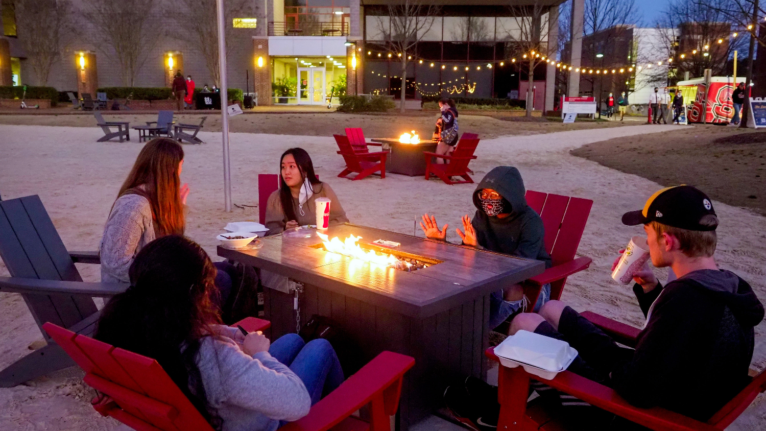Students warm up and enjoy dinner at their fire pit at the Den at Harris Field. Photo by Becky Kirkland.