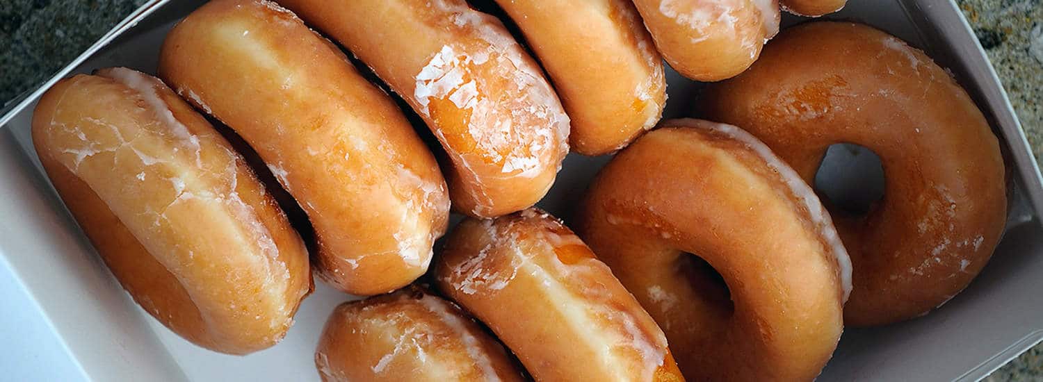 An overhead view of a box of Krispy Kreme donuts.