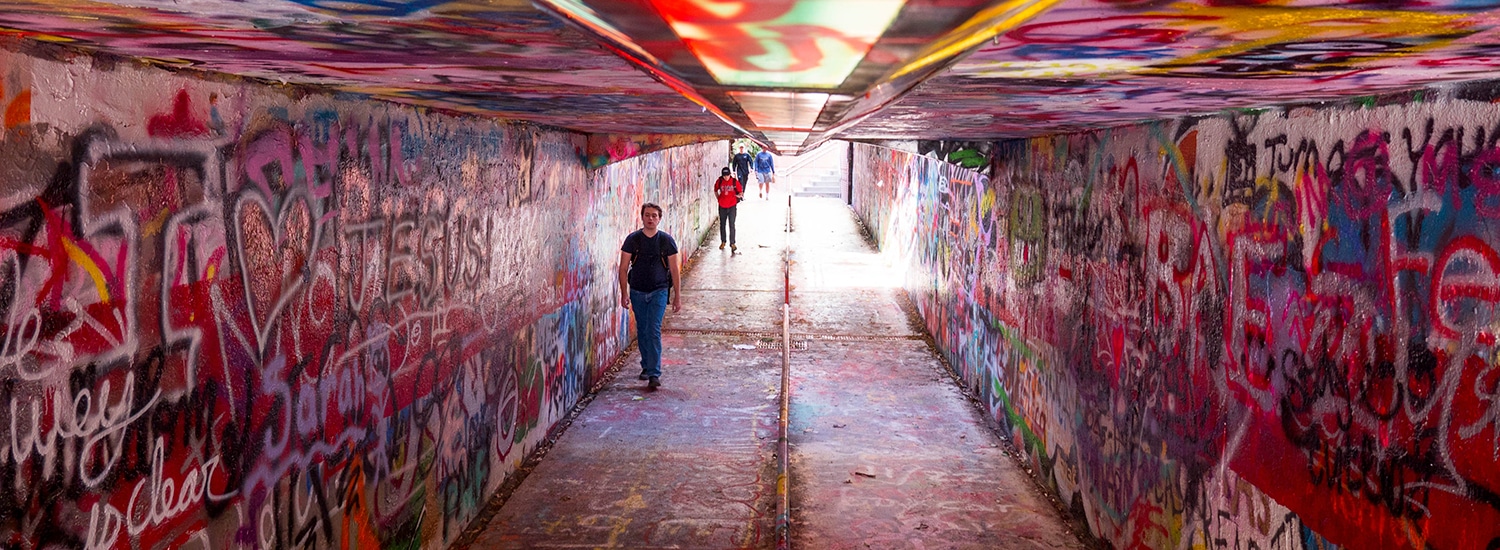 Students walk through a colorfully graffitied Free Expression Tunnel.