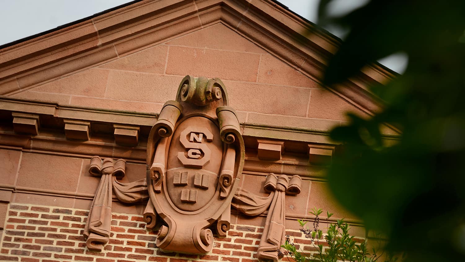 The facade of Holladay Hall shows an old, ornate NC State seal.