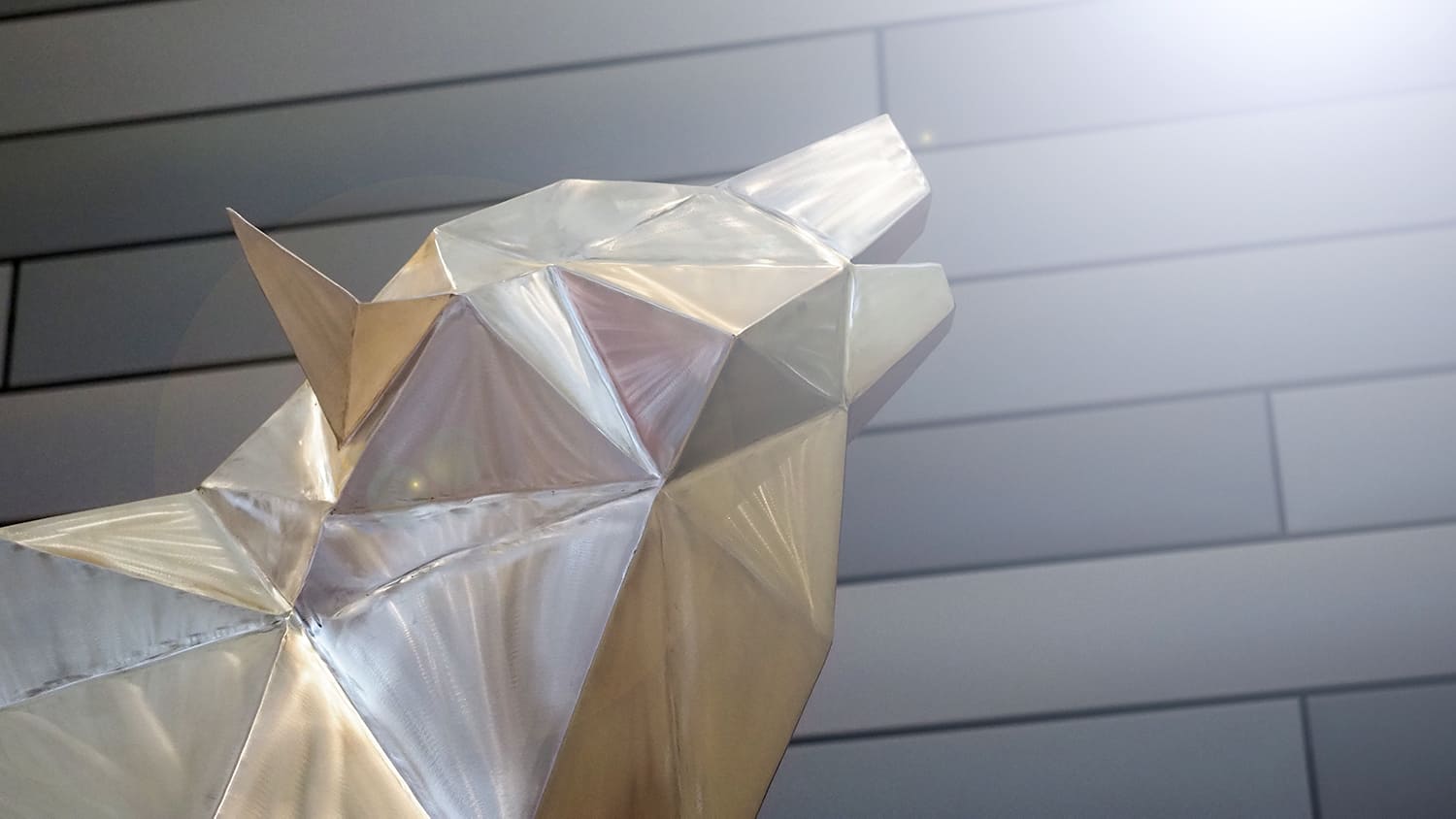 A silver geometric wolf statue sits in the main entrance of Reynolds Coliseum.