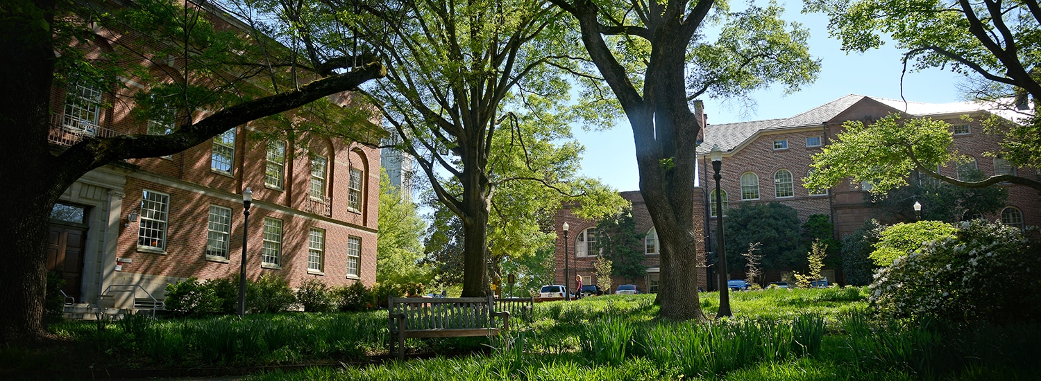 A shady view of Mary Yarbrough Court, surrounded by historic NC State buildings including Holladay Hall.