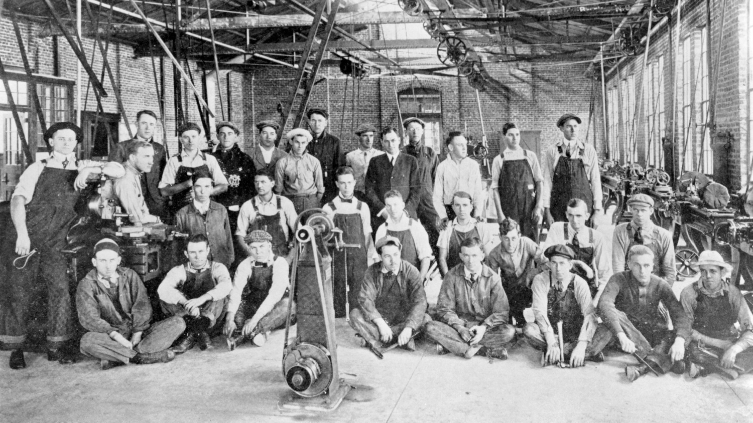 A black and white photo of a group of men posing with farming equipment. The bottom of the photo reads "Freshman Class 1909."
