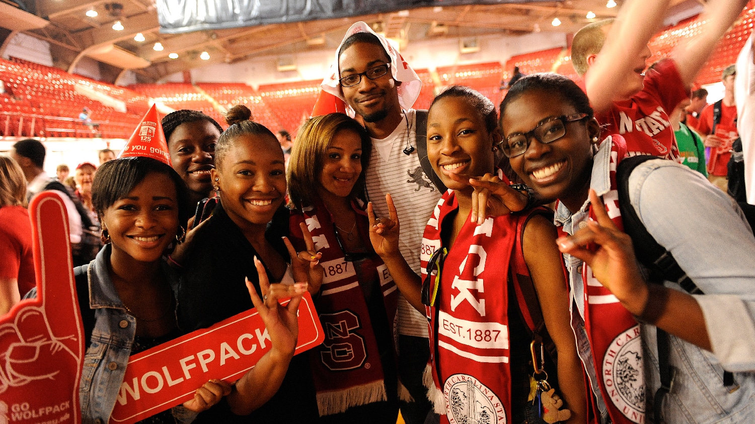 Student from the 2010s wear Wolfpack scarves during NC State's 125th birthday party in Reynolds Coliseum. 