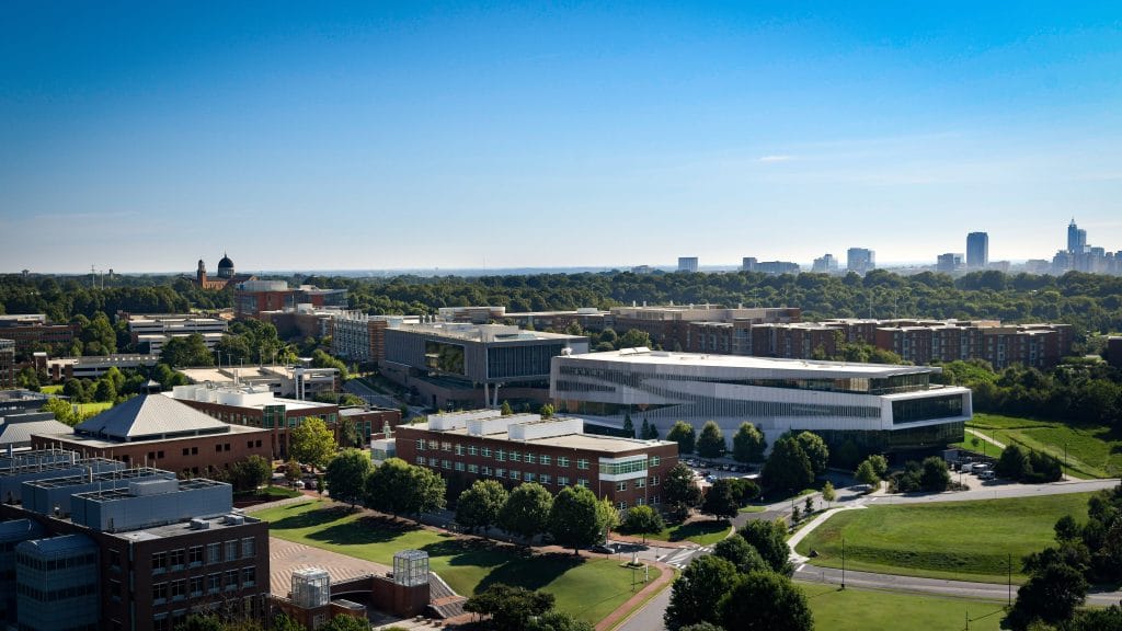 A photo highlighting the engineering buildings on Centennial Campus, in relation to downtown Raleigh skyline.