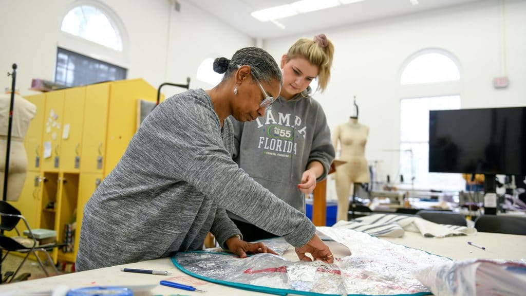 A faculty member instructs a student in a design lab.