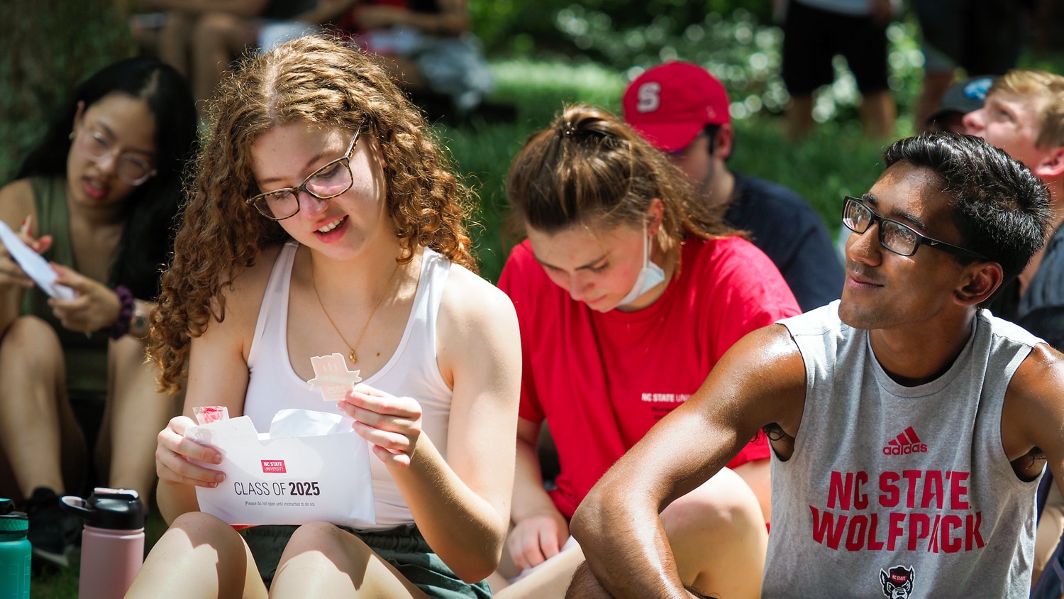 A group of NC State students attend convocation in 2021. A girl examines her "Class of 2025" envelope.