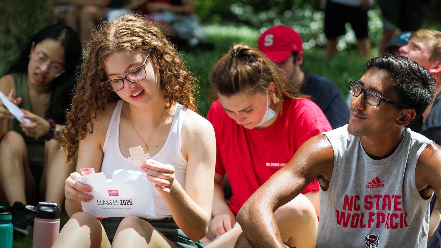 A group of NC State students attend convocation in 2021. A girl examines her "Class of 2025" envelope.