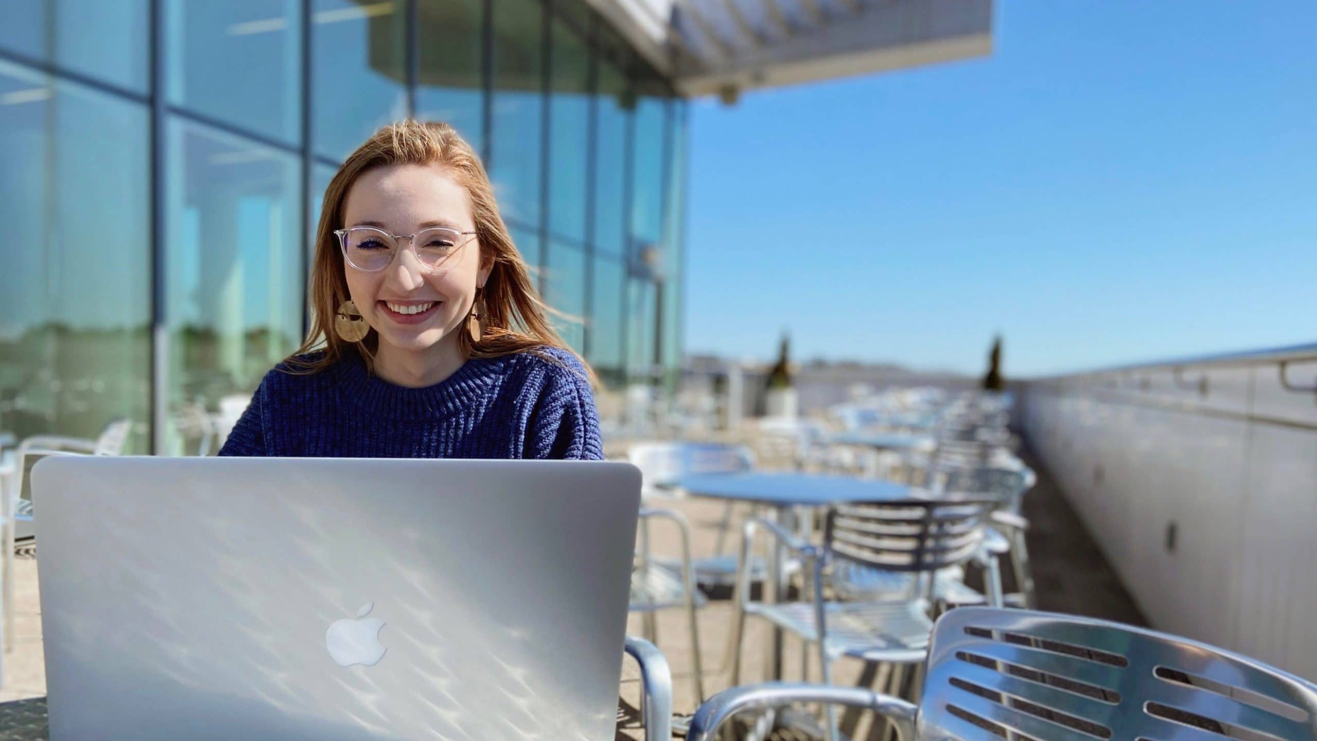 An NC&#160;State student at her laptop on the balcony of Hunt Library