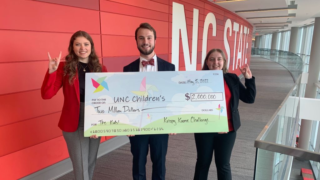 Three student directors of the Krispy Kreme Challenge pose with a check for the UNC Children's Hospital.