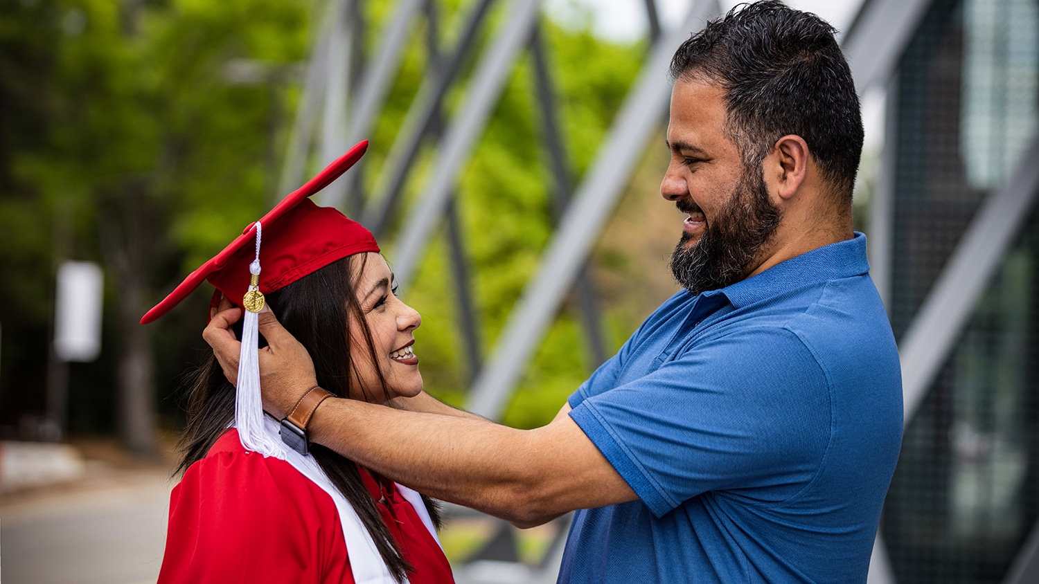 A man helps adjust the graduation cap on his partner's head.