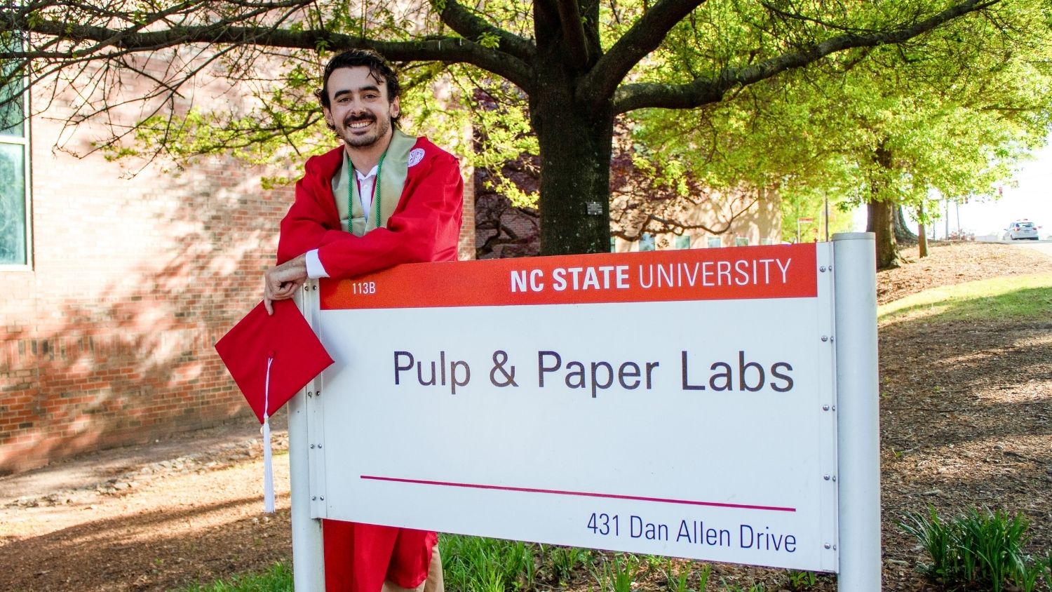 Brendan Tumpey, graduate of the College of Natural Resources, leans across a sign for the pulp and paper labs.