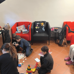 A student lounge at NC State Prague filled with children playing with toys.