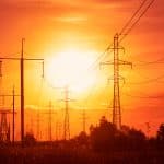 Rows of power lines lit by an orange sunset.