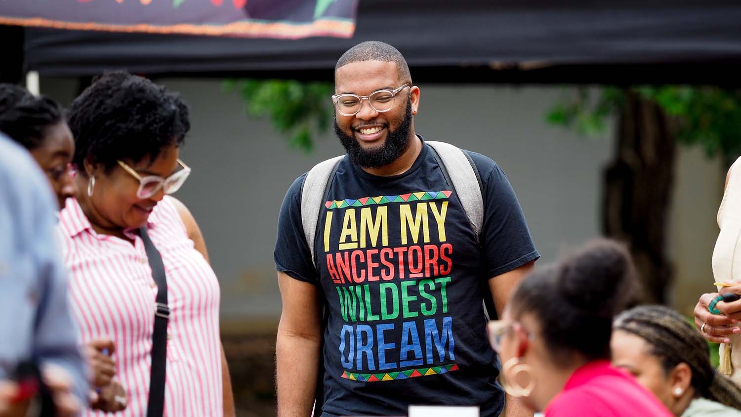 A student on Harris Field wears a shirt that says "I am my ancestors' wildest dream."
