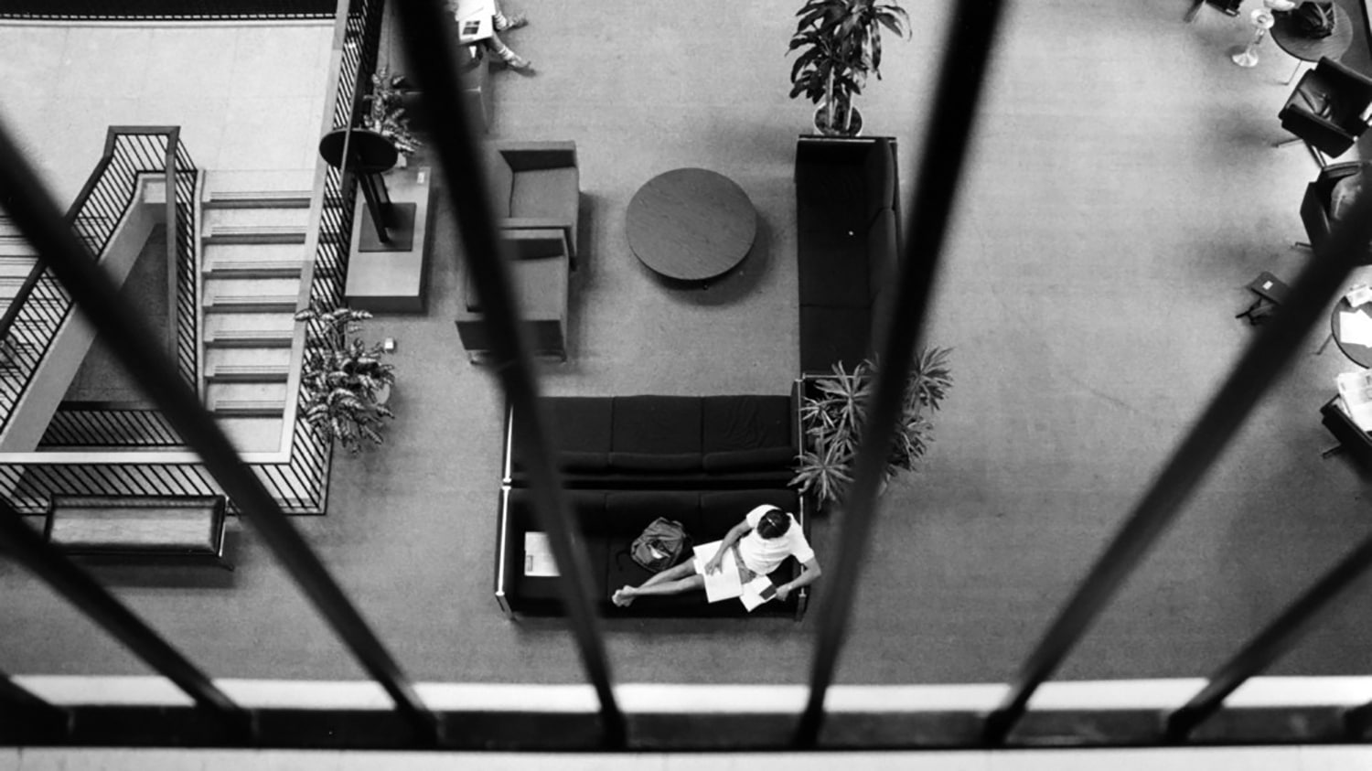 A black and white archival photo shows an overhead view of a student reading on a couch inside the University Student Center.
