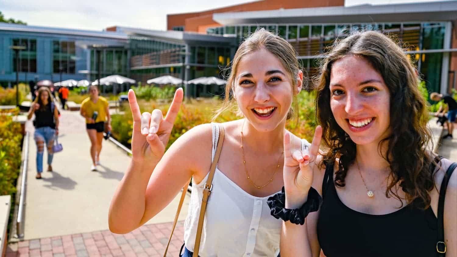 Two students hold up wolfies on Stafford Commons for the first week of class.