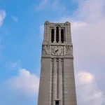 NC State's Belltower rising above Hillsborough Street on a sunny day.