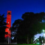 The Belltower lit in red with nearby Hillsborough Street.