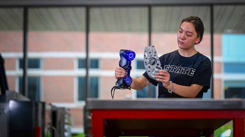 A student scans a metal part so it can be fabricated in the Fitts-Woolard building on Centennial Campus.