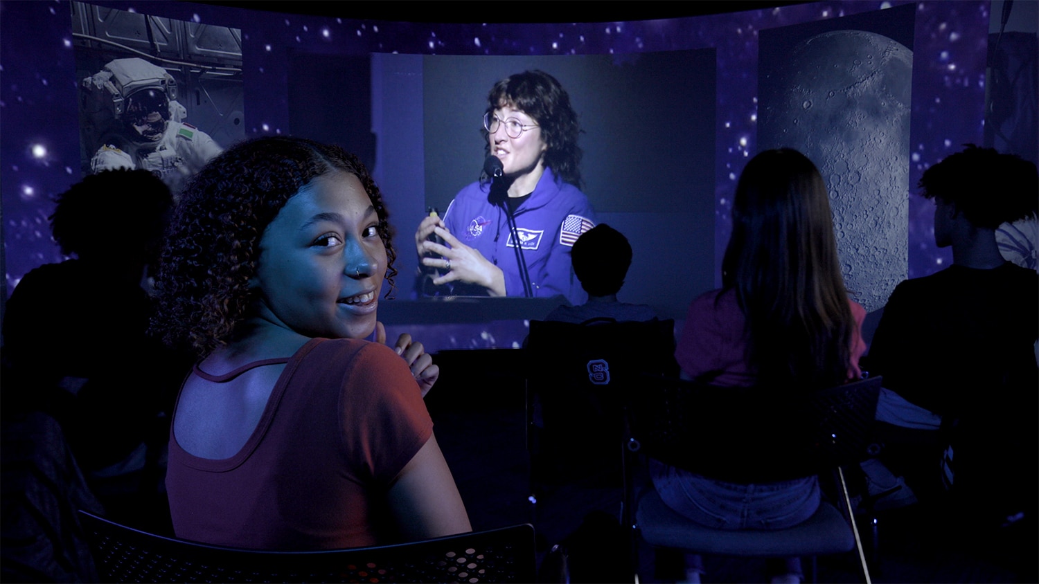 A student listens to Astronaut Christina Koch speak to her class in school on a video screen.