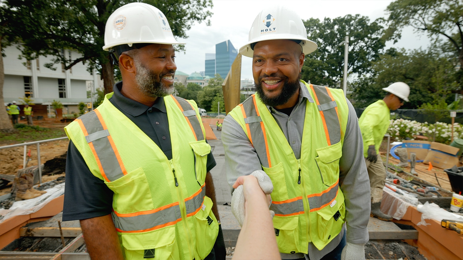 Torry and Terrence Holt, owners of Holt Brothers Construction, shake hands in front of a monument they helped install the new North Carolina Freedom Park.