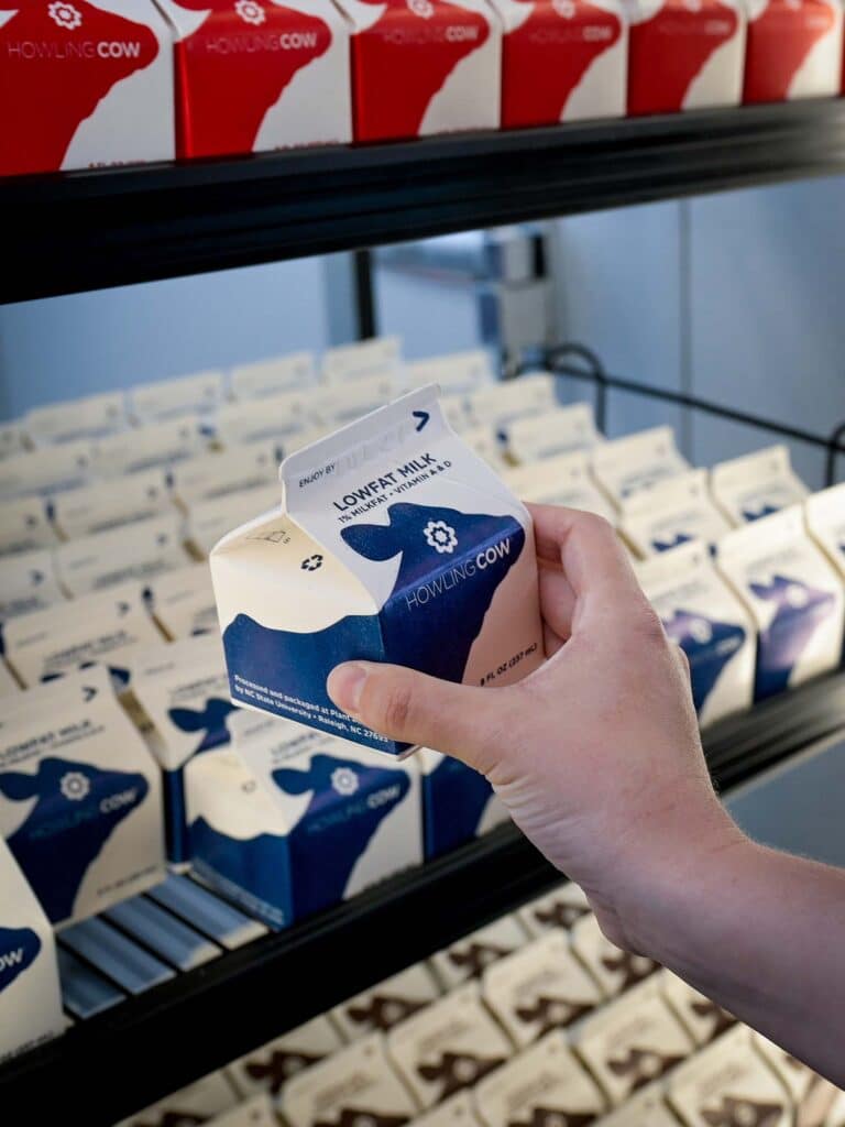 A hand picks out a carton of low fat milk from the fridge at the Howling Cow creamery.