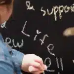 An NC State student writes on a chalkboard.