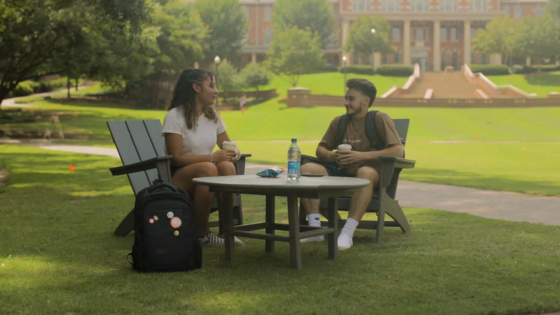 Two NC State students sit around a table with coffee on the Court of North Carolina.