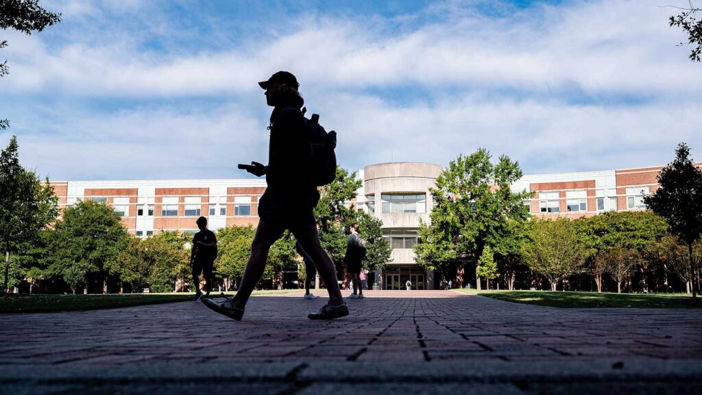 Students head to class on the path in front of Engineering Building I on the Oval on Centennial Campus.