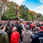 A large crowd gathers around and admires the new statue of David Thompson.