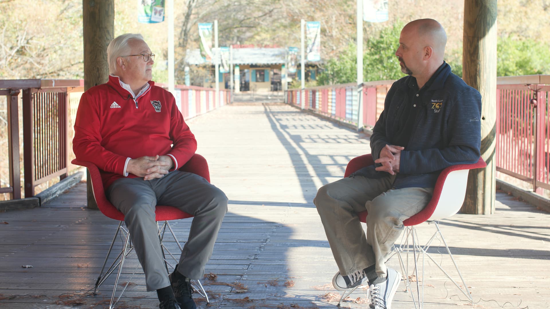 Chancellor Randy Woodson and alumnus Jb Minter sit at the North Carolina Zoo while filming an episode of Red Chair Chats.