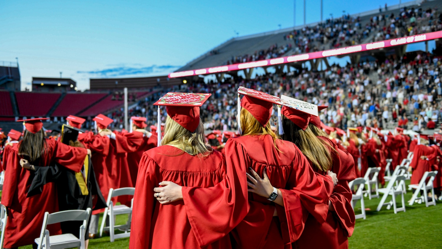 Students in red robes gather for commencement at Carter-Finley Stadium. 