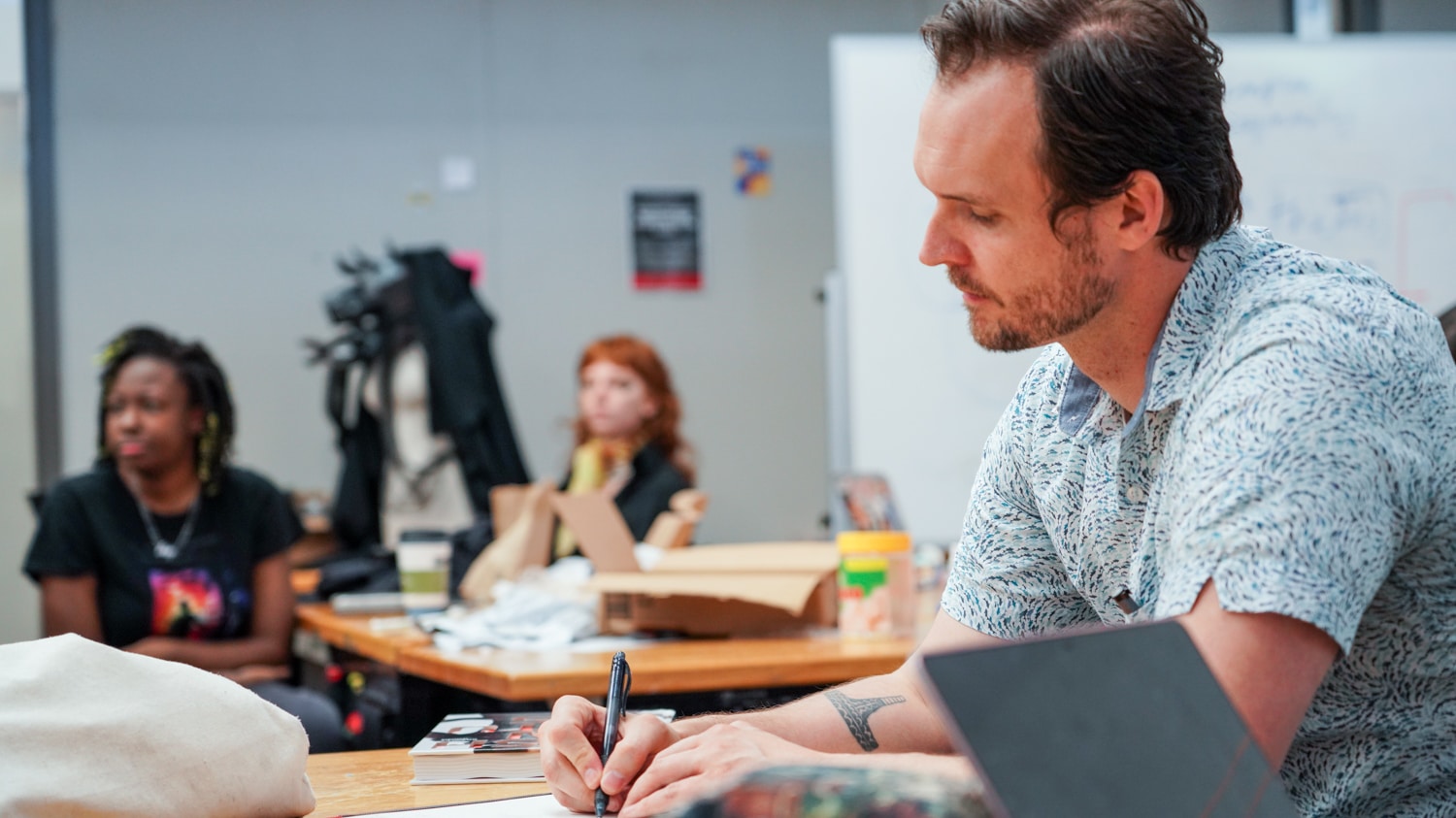 Justin Johnson takes notes as students present their work in a design class.