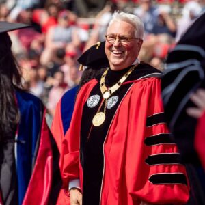 Randy Woodson smiles and greets 2025 graduates as they enter Carter-Finley Stadium.