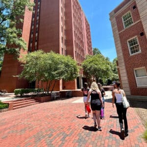 A group of students walk between brick residence halls on NC State's campus.