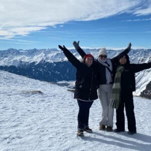 Three students in NC State's Global Leadership Minor pose together, arms raised, with snow-covered mountains in the background.