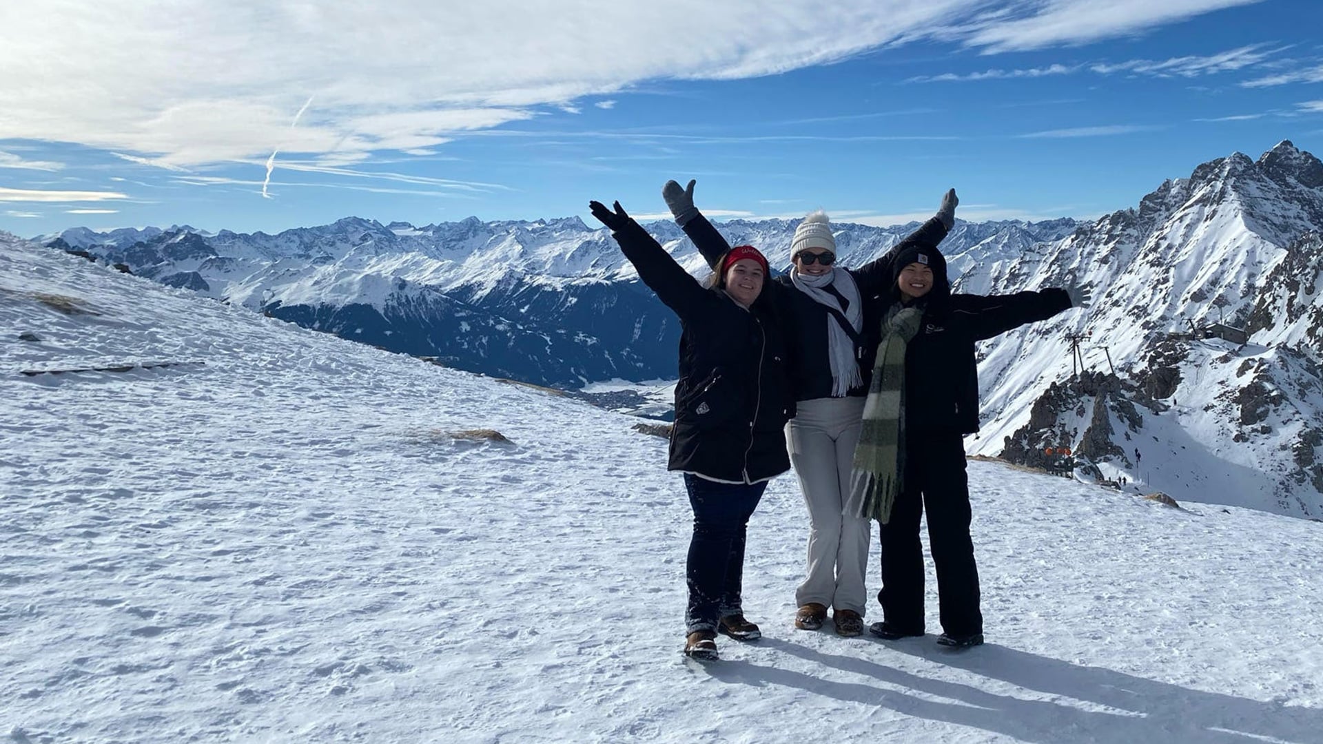 Three students in NC State's Global Leadership Minor pose together, arms raised, with snow-covered mountains in the background.