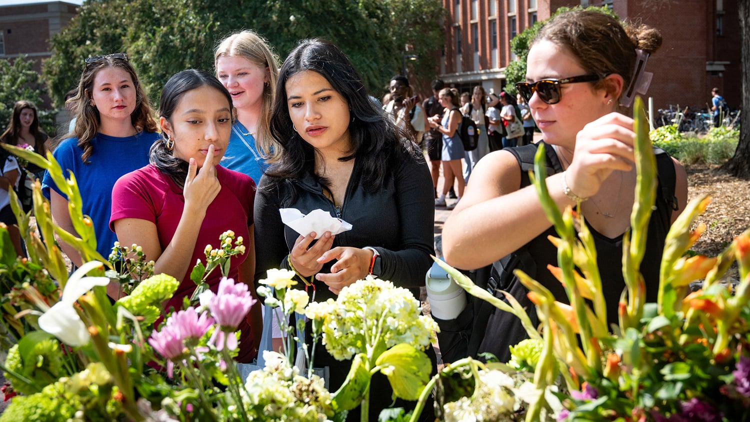 Students select cut flowers from a display on Wolf Plaza.