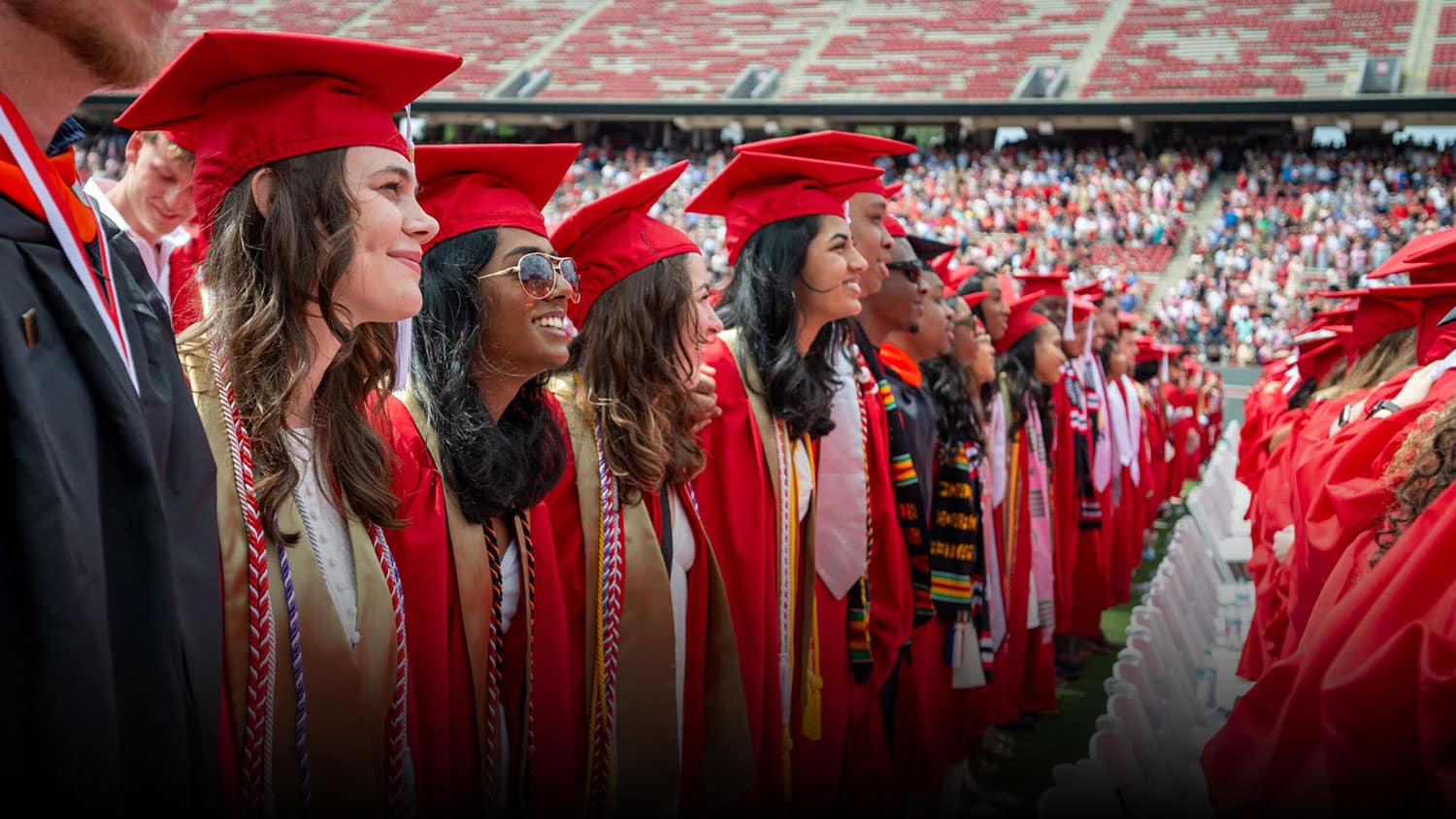NC State grads stand arm in arm at commencement.