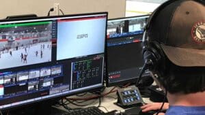 A member of WolfBytes Video Services works behind the scenes to broadcast an NC State Icepack hockey game.